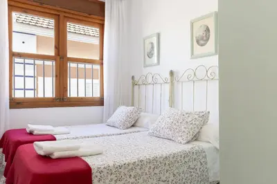 a white bedroom with two beds with towels on them at Apartamento Playa de Regla con terraza. 1. in Chipiona