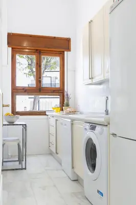 a white kitchen with a washing machine and a window at Apartamento Playa de Regla con terraza. 1. in Chipiona