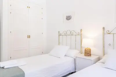 two beds in a bedroom with white walls at Apartamento Playa de Regla con terraza. 1. in Chipiona