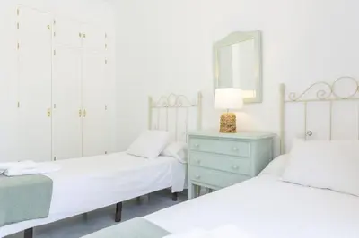 two beds in a bedroom with a mirror and a dresser at Luminoso y amplio piso en Chipiona. 5. in Chipiona