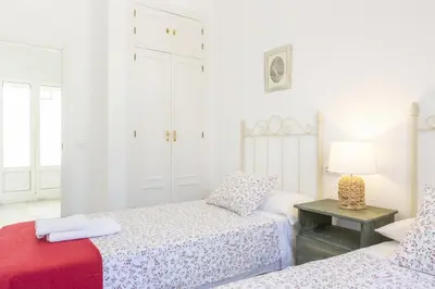 a white bedroom with two beds and a table at Luminoso y amplio piso en Chipiona. 5. in Chipiona