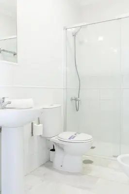 a white bathroom with a toilet and a shower at Luminoso y amplio piso en Chipiona. 5. in Chipiona