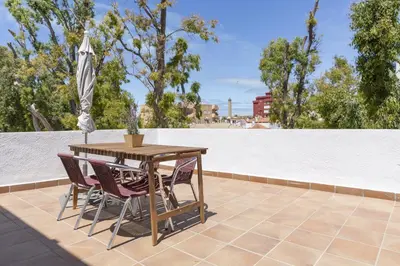 a table and chairs on a patio with an umbrella at Luminoso y amplio piso en Chipiona. 5. in Chipiona