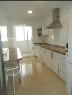 a kitchen with white cabinets and a table and chairs at CHIPIONA SOL Y PLAYA in Chipiona