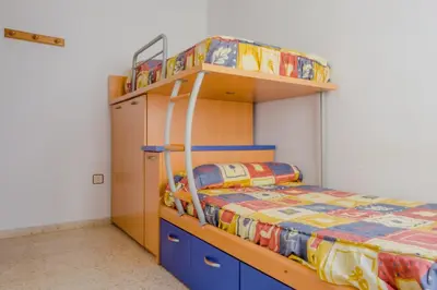 a bedroom with a bunk bed with blue cabinets and a bunk bed with a bed at La Barrosa con vistas al mar in Novo Sancti Petri