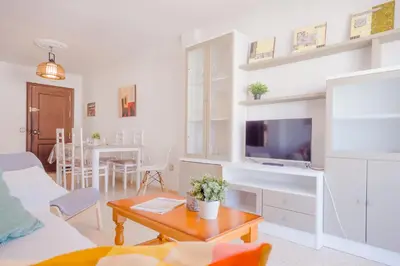 a living room with a couch and a tv and a table at La Barrosa con vistas al mar in Novo Sancti Petri