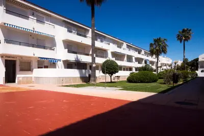 a large white building with palm trees in front of it at La Barrosa con vistas al mar in Novo Sancti Petri