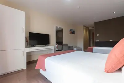 a bedroom with a white bed and a flat screen tv at Hotel Pradillo Conil in Conil de la Frontera