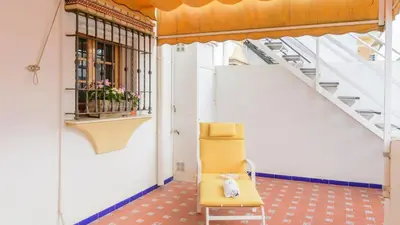 a yellow chair in a room with stairs at Apartamento Caracola Chipiona by Ruralidays in Chipiona