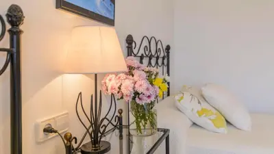 a vase of flowers on a table next to a bed at Apartamento Caracola Chipiona by Ruralidays in Chipiona