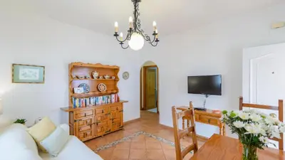 a living room with a table and a tv at Apartamento Caracola Chipiona by Ruralidays in Chipiona