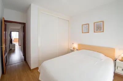 a white bedroom with a large bed and a hallway at Piso SieteRevueltas in Sanlúcar de Barrameda