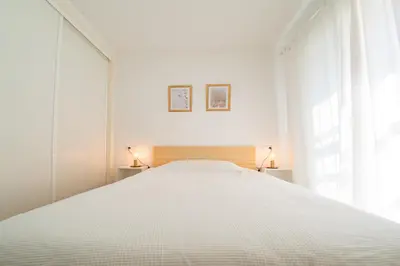 a white bedroom with a large white bed with two lamps at Piso SieteRevueltas in Sanlúcar de Barrameda