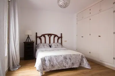 a white bedroom with a bed with a wooden headboard at Apartamento Albareda Centro in El Puerto de Santa María