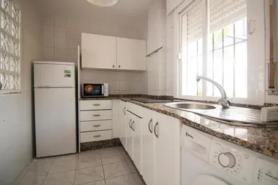 a white kitchen with a sink and a refrigerator at Apartamento Albareda Centro in El Puerto de Santa María