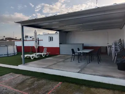 a patio with a table and chairs under a roof at La Casa de la Abuela Jesús in Sanlúcar de Barrameda
