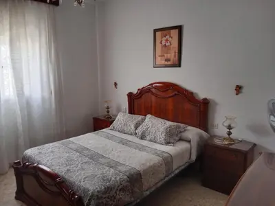 a bedroom with a large bed with a wooden headboard at La Casa de la Abuela Jesús in Sanlúcar de Barrameda