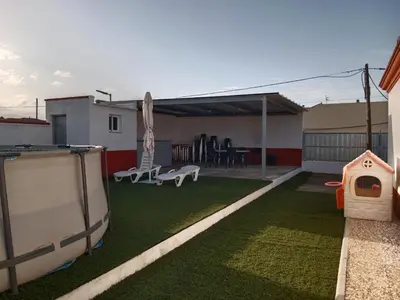 a small backyard with a lawn with a dog house at La Casa de la Abuela Jesús in Sanlúcar de Barrameda
