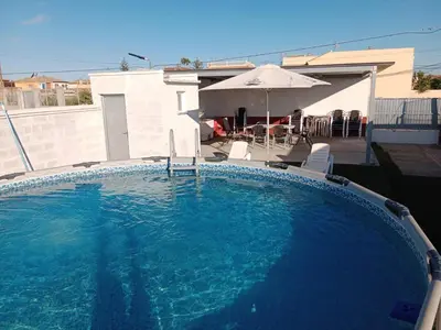 a large swimming pool with chairs and an umbrella at La Casa de la Abuela Jesús in Sanlúcar de Barrameda