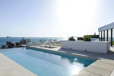 a swimming pool with chairs and the ocean in the background at Casa Vista Azul in El Puerto de Santa María
