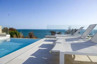 a row of white lounge chairs sitting next to a swimming pool at Casa Vista Azul in El Puerto de Santa María