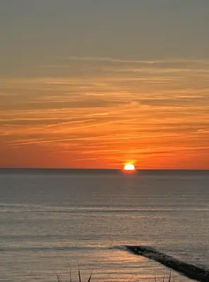 a sunset over the ocean with the sun in the distance at Casa Vista Azul in El Puerto de Santa María