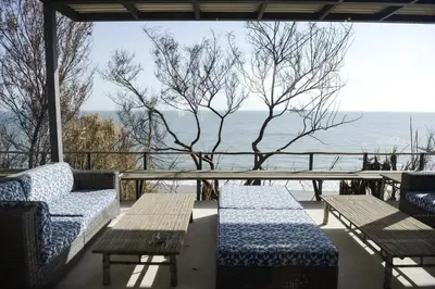 a porch with two benches and a table and the ocean at Casa Vista Azul in El Puerto de Santa María