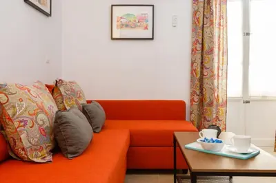 a living room with an orange couch and a table at Apartamento FEDUCHY 10 min de la playa 2 baños in Cádiz