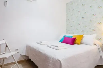 a white bed with colorful pillows on top of it at Apartamento FEDUCHY 10 min de la playa 2 baños in Cádiz