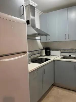 a kitchen with white cabinets and a white refrigerator at Apartamento FEDUCHY 10 min de la playa 2 baños in Cádiz