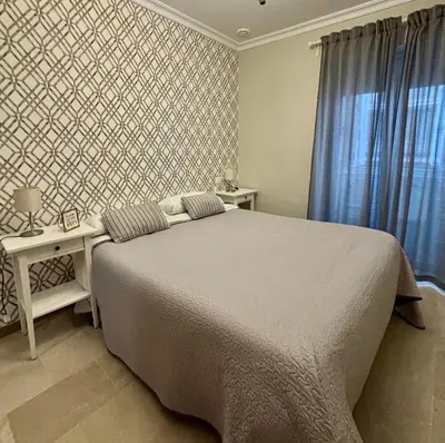 a bedroom with a bed and a table and a window at Apartamento FEDUCHY 10 min de la playa 2 baños in Cádiz