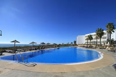 a large swimming pool with chairs and a building at Garbí Costa Luz in Conil de la Frontera