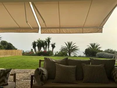 a couch under a tent with palm trees in a field at Casa Sol de Mar in El Puerto de Santa María