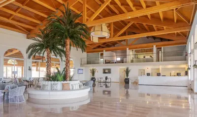 a lobby with a palm tree in the middle at Ilunion Sancti Petri in Chiclana de la Frontera
