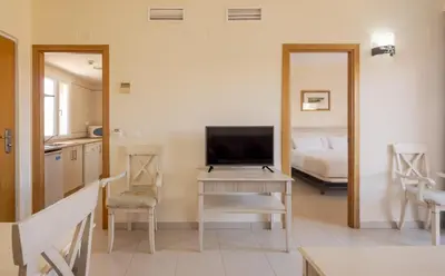 a living room with a television and a table with a desk at Ilunion Sancti Petri in Chiclana de la Frontera