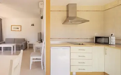a kitchen with a microwave and a living room at Ilunion Sancti Petri in Chiclana de la Frontera