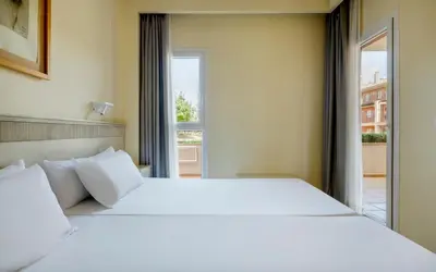 a bedroom with a large white bed and a window at Ilunion Sancti Petri in Chiclana de la Frontera