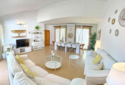 a living room with white furniture and a dining room at Villa Los Pinares de Monaco en Roche, Conil, Cádiz in Conil de la Frontera