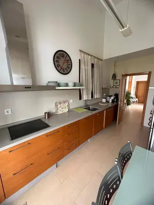 a kitchen with wooden cabinets and a clock on the wall at Villa Los Pinares de Monaco en Roche, Conil, Cádiz in Conil de la Frontera