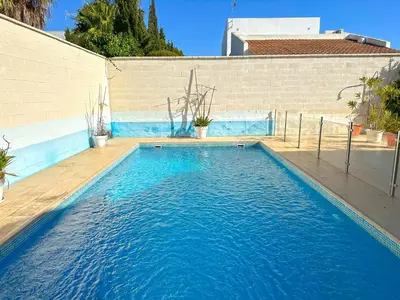 a swimming pool with blue water in front of a house at Villa Los Pinares de Monaco en Roche, Conil, Cádiz in Conil de la Frontera
