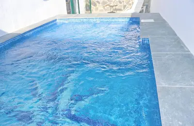 a large blue swimming pool with a chair in it at Chalet La Higuerita in Conil de la Frontera