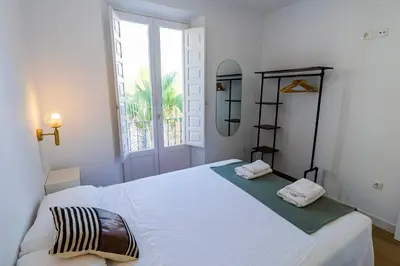 a bedroom with a large white bed with a window at Apartamentos La Cruz Verde in Cádiz