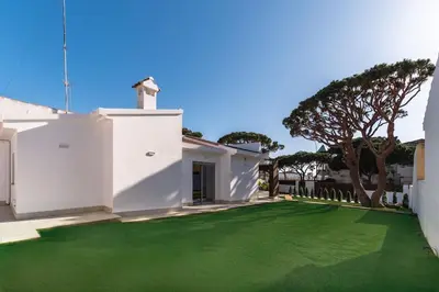a white house with a green lawn at SIAT VIVIENDAS Villa carretera LA BARROSA in Chiclana de la Frontera