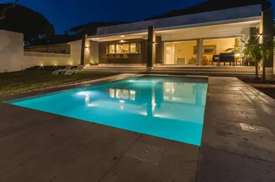 a swimming pool in front of a house at night at SIAT VIVIENDAS Villa carretera LA BARROSA in Chiclana de la Frontera