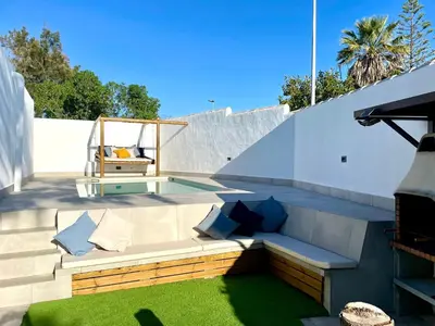 a patio with a bench with pillows and a swing at Minichalet El Molino 1 in Chiclana de la Frontera