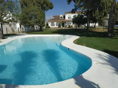 a swimming pool in a yard with a house in the background at Hacienda Laguna Seca - Apart. Jazmin in Chiclana de la Frontera