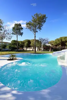 a pool of blue water with trees in the background at Hacienda Laguna Seca - Apart. Jazmin in Chiclana de la Frontera