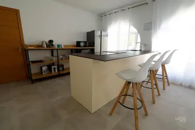 a kitchen with a counter and some white chairs at Hacienda Laguna Seca - Apart. Buganvilla in Chiclana de la Frontera