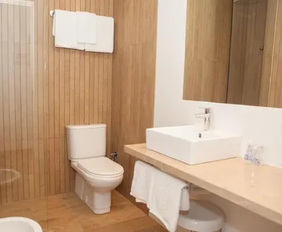 a bathroom with a white toilet and a sink at Hotel Puerto Bahía & Spa in El Puerto de Santa María