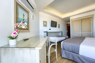 a hotel room with two beds and a desk at Hotel Puerto Bahía & Spa in El Puerto de Santa María